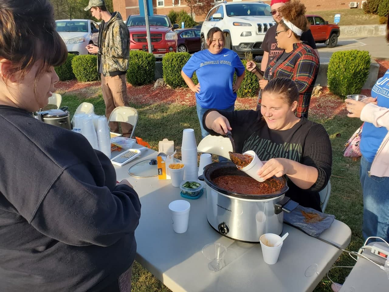 College students serving chili into styrofoam cups in the outdoors